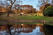 PAINSWICK ROCOCO GARDEN, GLOUCESTERSHIRE: THE RED HOUSE AND EXEDRA SEEN FROM THE LAKE, POND, POOL, REFLECTIONS, REFLECTED, FEBRUARY