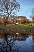 PAINSWICK ROCOCO GARDEN, GLOUCESTERSHIRE: THE RED HOUSE AND EXEDRA SEEN FROM THE LAKE, POND, POOL, REFLECTIONS, REFLECTED, FEBRUARY