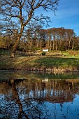 PAINSWICK ROCOCO GARDEN, GLOUCESTERSHIRE: THE EXEDRA SEEN FROM THE LAKE, POND, POOL, REFLECTIONS, REFLECTED, FEBRUARY