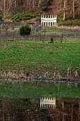 PAINSWICK ROCOCO GARDEN, GLOUCESTERSHIRE: THE EXEDRA SEEN FROM THE LAKE, POND, POOL, REFLECTIONS, REFLECTED, FEBRUARY