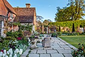 THE OLD RECTORY WARBLETON, EAST SUSSEX, APRIL, LAWN, CLIPPED YEW TOPIARY, TULIPS, TERRACE, PATIO, WICKER TABLE AND CHAIRS