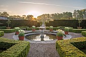 COUGHTON COURT, WARWICKSHIRE: MAY, CIRCULAR POOL, FOUNTAIN, TERRACOTTA CONTAINERS WITH TULIP WORLD FRIENDSHIP, YEW HEDGES, HEDGING, SUNRISE