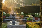 COUGHTON COURT, WARWICKSHIRE: MAY, CIRCULAR POOL, FOUNTAIN, TERRACOTTA CONTAINERS WITH TULIP WORLD FRIENDSHIP, YEW HEDGES, HEDGING, SUNRISE