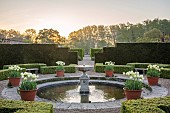 COUGHTON COURT, WARWICKSHIRE: MAY, CIRCULAR POOL, FOUNTAIN, TERRACOTTA CONTAINERS WITH TULIP WORLD FRIENDSHIP, YEW HEDGES, HEDGING, SUNRISE