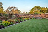 COUGHTON COURT, WARWICKSHIRE: MAY, LAWN, LONG BORDER, WALLED GARDEN, SUNRISE, TULIP BRONZE PERFECTION, EUPHORBIA POLYCHROMA, WOODEN BENCH, SEAT