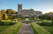 COUGHTON COURT, WARWICKSHIRE: MAY, CIRCULAR POOL, FOUNTAIN, TERRACOTTA CONTAINERS WITH TULIP WORLD FRIENDSHIP, YEW HEDGES, HEDGING, SUNRISE, CHURCH