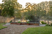 COUGHTON COURT, WARWICKSHIRE: MAY, MIST RISING OF POND, LAKE, MORNING LIGHT, TERRACOTTA CONTAINERS PLANTED WITH TULIP WORLD FRIENDSHIP, WALLED GARDEN