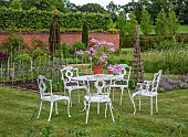 ASHBY MANOR HOUSE, NORTHAMPTONSHIRE: MAY, THE WALLED GARDEN, WHITE METAL TABLE AND CHAIRS, TERRACOTTA CONTAINER PLANTED WITH PELARGONIUMS