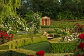 HIGHNAM COURT, GLOUCESTERSHIRE: JUNE, VIEW OF THE TEMPLE SEEN FROM THE ROSE GARDEN, WOODEN BENCH, SEAT, SWAGGED WHITE ROSES