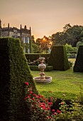 RENISHAW HALL & GARDENS, DERBYSHIRE: SUNRISE OVER THE GARDEN SEEN FROM THE TOP LAWN, THE FIRST CANDLE, MARBLE FOUNTAIN, ROSES, CLIPPED TOPIARY YEW