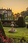 RENISHAW HALL & GARDENS, DERBYSHIRE: SUNRISE OVER THE GARDEN SEEN FROM THE TOP LAWN, THE FIRST CANDLE, MARBLE FOUNTAIN, ROSES, CLIPPED TOPIARY YEW