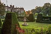 RENISHAW HALL & GARDENS, DERBYSHIRE: SUNRISE OVER THE GARDEN SEEN FROM THE TOP LAWN, THE FIRST CANDLE, MARBLE FOUNTAIN, ROSES, CLIPPED TOPIARY YEW