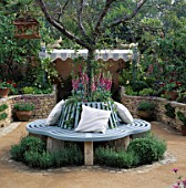 ORNATE BLUE TREE SEAT WITH CUSHIONS SURROUNDS PRUNUS AUTUMNALIS.  DESIGNER BUNNY GUINNESS/DGAA HOMELIFE GARDEN CHELSEA 97