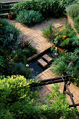 TERRACOTTA_PAVING_AND_WATER_FEATURE_IN_SEASIDE_GARDEN_WITH_BLUE_AND_WHITE_AGAPANTHUS__AFRICANUS_EUPH