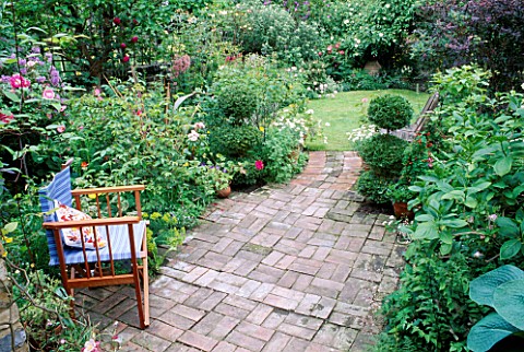 BLUE_CHAIR_IN_SECLUDED_CORNER_OF_BRICK_TERRACE_LOOKING_DOWN_THE_GARDEN_TOWARDS_CONTAINERS_WITH_CLIPP
