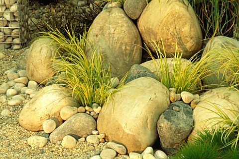 GRASSES_GROW_UP_AMONGST_ARRANGEMENT_OF_LARGE_AND_SMALL_BOULDERS_IN_GRAVEL_IN_MODERN_ROOF_GARDEN__DES