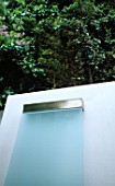 SIMPLE WATER FEATURE: WATER TRICKLES OVER STAINLESS STEEL SILL AND DOWN A SHEET OF GLASS IN CHARLES WORTHINGTONS MINIMALIST GARDEN. DESIGNER:STEPHEN WOODHAMS