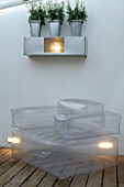 LIGHTS SHINE THROUGH INFLATABLE CHAIR ON WOODEN DECKING IN CHARLES WORTHINGTONS MINIMALIST GARDEN.  DESIGNER:STEPHEN WOODHAMS (WHITE STOCKS IN ALUMINIUM CONTAINERS)
