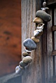 STRING OF SEA-WORN PEBBLES WRAPPED AROUND A WOODEN POST IN DESIGNER STEPHEN WOODHAMS OWN ROOF GARDEN.