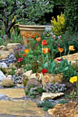 DRY CREEK BED WITH CERAMIC POTS BY KEEYLA MEADOWS PLANTED WITH ORANGE TULIPS