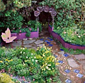 KEEYLA MEADOWS GARDEN SAN FRANCISCO. BUTTERFLY BENCH  YELLOW TULIPS AND A COPPER MORNING GLORY ARCH.