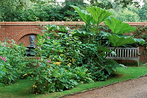 WATER_FOUNTAIN_IN_WALL_WITH_GUNNERA_MANICATA__WOODEN_BENCH_AND_BALSAM_MOLESHILL_HOUSE__SURREY