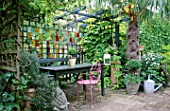 COURTYARD GARDEN: TABLE AND SEATS UNDER SHADY PERGOLA WITH STAINED GLASS SCREEN BEHIND. DESIGNER: JONATHAN BAILLIE