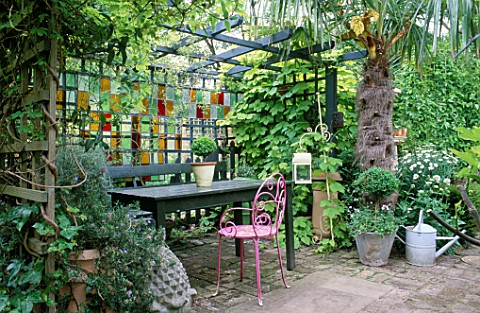 COURTYARD_GARDEN_TABLE_AND_SEATS_UNDER_SHADY_PERGOLA_WITH_STAINED_GLASS_SCREEN_BEHIND_DESIGNER_JONAT