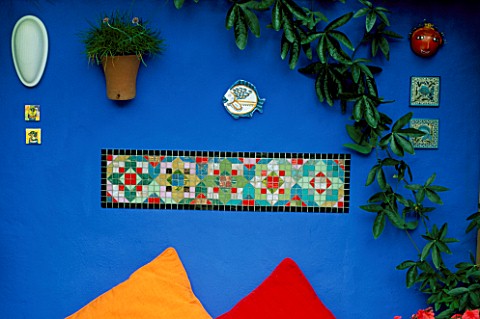 DECORATIVE_FEATURE_BRIGHTLY_COLOURED_MOSAIC_SET_IN_ULTRAMARINE_BLUE_WALL_BENEATH_ON_A_WOODEN_BENCH_A