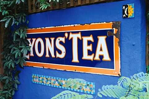DECORATIVE_FEATURE_A_LYONS_TEA_SIGN__A_MOSAIC_AND_A_SMALL_PAINTED_MEXICAN_TILE_ON_AN_ULTRAMARINE_BLU