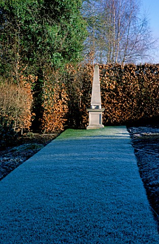 A_LONG_STRIP_OF_FROSTED_LAWN_LEADS_TO_AN_OBELISK_IN_FRONT_OF_A_BEECH_HEDGE_ARROW_COTTAGE__HEREFORDSH