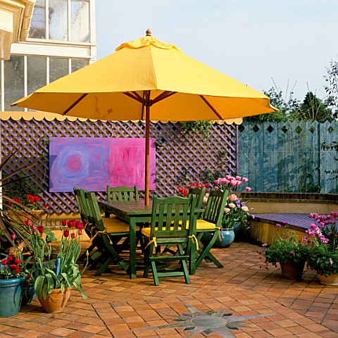 A_PLACE_TO_SIT_YELLOW_PARASOL_SHADES_GREEN_SEATING_WITH_CONTAINERS_OF_TULIPA_LILAC_PERFECTION__ANGEL