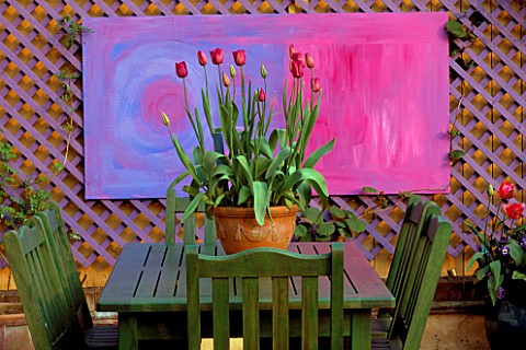 A_PLACE_TO_SIT__GREEN_TABLE__CHAIRS_WITH_TERRACOTTA_CONTAINER_PLANTED_WITH_RED_TULIPS__IN_THE_BGROUN