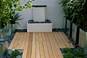 WATER FEATURE: MODERN GARDEN WITH FOUNTAIN  GALVANISED METAL CONTAINERS  WHITE-WASHED WALLS AND LIGHT BROWN WOODEN DECKING   DESIGNED BY PATRICK WYNNIATT-HUSEY AND PATRICK CLARKE