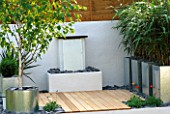 WATER FEATURE: MODERN GARDEN WITH FOUNTAIN  GALVANISED METAL CONTAINERS  WHITE-WASHED WALLS  LIGHT BROWN WOODEN DECKING  BETULA UTILIS AND PSEUDOSASA JAPONICA