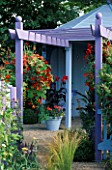 PURPLE PERGOLA WITH HANGING BASKET OF MIXED TROPAEOLUMS & CANNA RICHARD WALLACE IN BLUE CONTAINER IN GARDENING WHICH/ MET. POLICE A SAFE HAVEN. HAMPTON 1999.