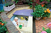 PATIO WITH ROBERT PLAYING IN SANDPIT MADE FROM BREEZE BLOCKS AND RENDERED WITH PLASTER.SOFTWOOD WOODEN DECKING COVERS THE SANDPIT WHEN NOT IN USE. DAHLIAS IN TERRACOTTA POTS