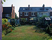 VIEW FROM THE BACK OF THE NICHOLS GARDEN IN READING: BLUE FENCES  COVERED SEAT PAINTED MAUVE AND SWINGS ON LEFT