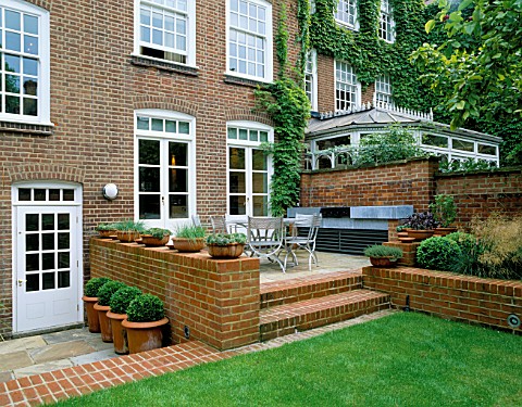 VIEW_FROM_THE_LAWN_TOWARDS_THE_HOUSE_WITH_METAL_GARDEN_FURNITURE_AND_BARBEQUE_ON_RAISED_PATIO_AND_TE