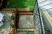 OVERVIEW OF GARDEN WITH SIDE OF CONSERVATORY  LAWN  PAVING  AND BRICK WORK. TERRACOTTA CONTAINERS HOLD BOX BALLS. MODERNISTS TOWN GARDEN DESIGNED BY CHRISTOPHER BRADLEY-HOLE