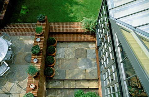 OVERVIEW_OF_GARDEN_WITH_SIDE_OF_CONSERVATORY__LAWN__PAVING__AND_BRICK_WORK_TERRACOTTA_CONTAINERS_HOL