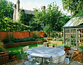 VIEW ACROSS MODERNISTS TOWN GARDEN WITH METAL GARDEN FURNITURE AND CONSERVATORY IN THE FOREGROUND. LAWN  BRICK WALL BED AND ITALIAN POLISHED PLASTER WALL IN B/G.