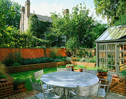 VIEW_ACROSS_MODERNISTS_TOWN_GARDEN_WITH_METAL_GARDEN_FURNITURE_AND_CONSERVATORY_IN_THE_FOREGROUND_LA