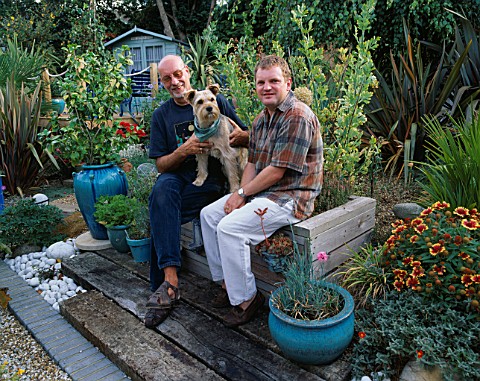 ROBIN_GREEN_AND_RALPH_CADE_WITH_THEIR_DOG_RUFUS_SIT_ON_THE_WEATHERED_WOODEN_HERB_BENCH_IN_THEIR_SEAS