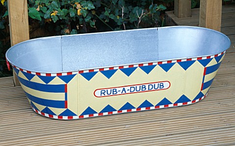 DECORATIVELY_PAINTED_OLD_TIN_BATH_ON_RIBBED_DECKING_THE_BATH_DOUBLES_AS_BOTH_A_PADDLING_POOL__WATER_