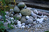 WATER FEATURE: A PILE OF SEA WORN PEBBLES AND GRAVEL CREATE A SMALL FOUNTAIN. ROBIN GREEN & RALPH CADES SEASIDE STYLE GARDEN  LONDON.