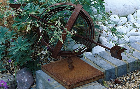 GERANIUM_JOHNSONS_BLUE__WEAVES_ITS_WAY_THROUGH_A_RUSTED_WEATHER_VANE_ROBIN_GREEN_AND_RALPH_CADES_SEA