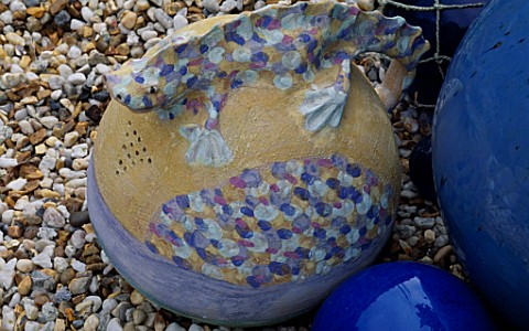 A_CERAMIC_SALAMANDER_JUG_INSPIRED_BY_GAUDI_WITH_COBALT_CERAMIC_AND_GLASS_BALLS_ON_A_BED_OF_SHINGLE_R