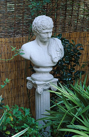 A_CLASSICAL_BUST_MOUNTED_ON_A_COLUMN_CREATES_A_FOCAL_POINT_IN_FRONT_OF_A_SPLIT_BAMBOO_AND_WOVEN_WICK