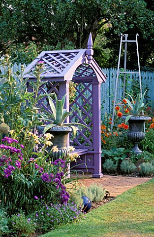 MAUVE_WOODEN_SEAT_WITH_SILVER_PAINTED_METAL_URNS_PLANTED_WITH_AGAVES_IN_BORDER_ARE_ALLIUM_GIGANTEUM_